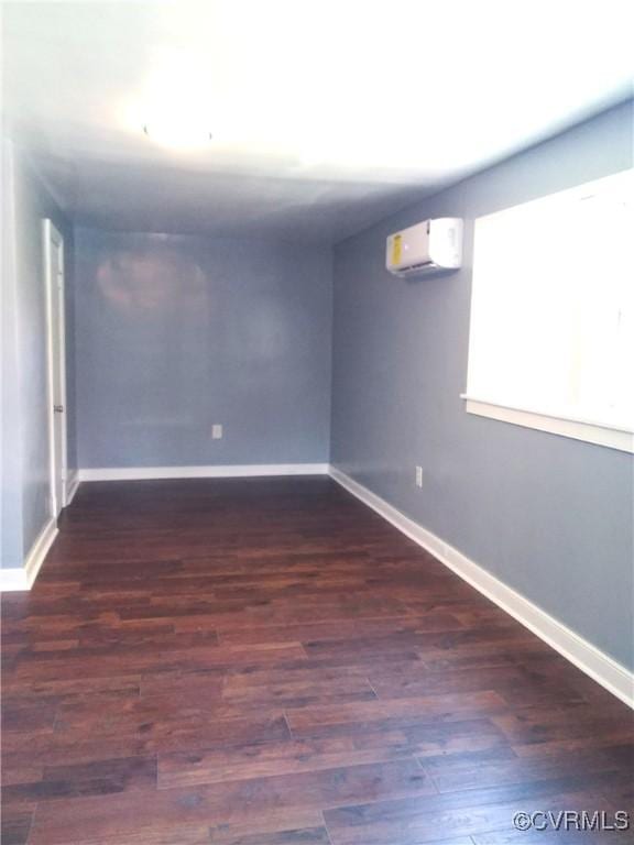 basement with an AC wall unit, baseboards, and wood finished floors