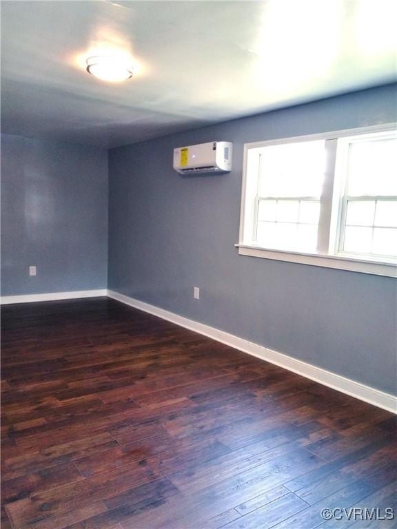 empty room with baseboards, a wall mounted air conditioner, and dark wood-style floors