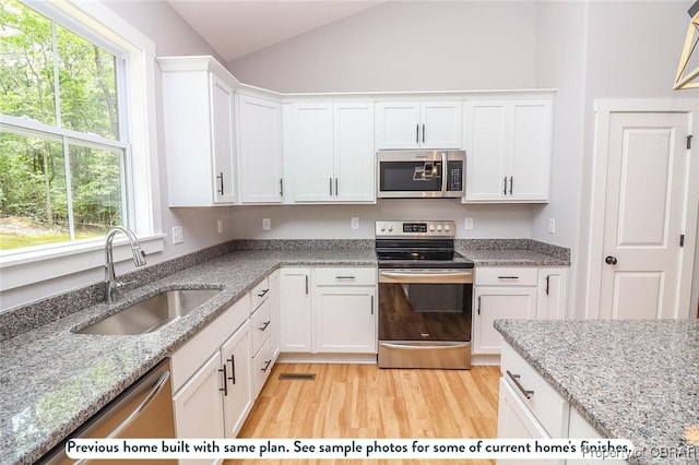 981 Knights Landing Dr, Heathsville, VA 22473 - kitchen with appliances with stainless steel finishes, vaulted ceiling, healthy amount of natural light, white cabinetry, and light wood-style floors