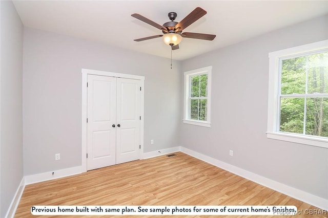 981 Knights Landing Dr, Heathsville, VA 22473 - unfurnished bedroom with multiple windows, light wood-type flooring, a closet, and a ceiling fan