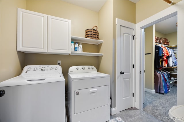 laundry area with light carpet, cabinet space, light tile patterned flooring, and washing machine and dryer