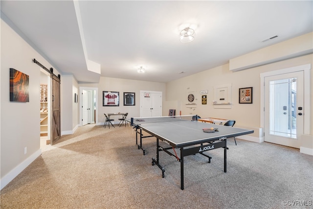 recreation room featuring visible vents, light carpet, a barn door, and baseboards