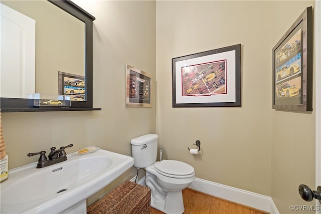 bathroom featuring wood finished floors, toilet, baseboards, and a sink
