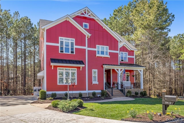 view of front of property with covered porch, board and batten siding, a front yard, and driveway