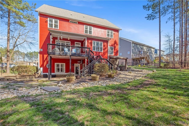 rear view of house with a deck, fence, a yard, and stairs