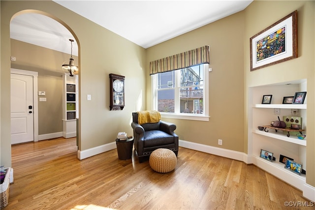 living area with light wood finished floors, arched walkways, and baseboards
