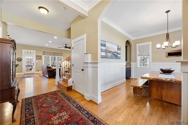 corridor featuring a healthy amount of sunlight, light wood finished floors, stairs, and arched walkways
