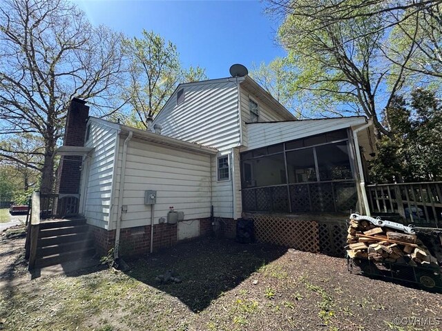 rear view of house featuring a sunroom and a chimney