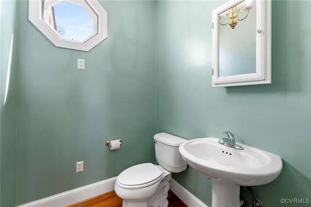 bathroom with baseboards, toilet, and a sink