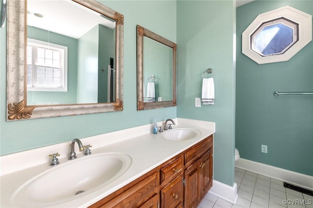 bathroom with double vanity, toilet, tile patterned flooring, and a sink