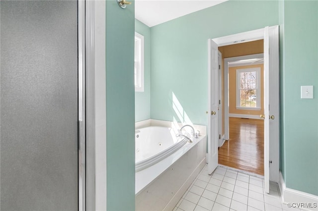 bathroom with tile patterned floors, baseboards, and a jetted tub