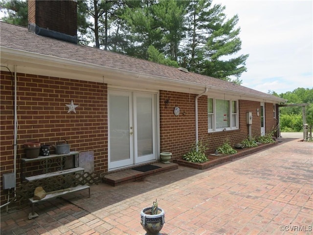9616 Sunnyside Rd, Mc Kenney, VA 23872 - property entrance with roof with shingles, brick siding, a patio, and a chimney