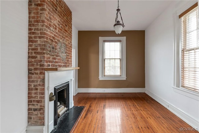 2200 E Grace St, Richmond, VA 23223 - unfurnished living room with baseboards, a fireplace with raised hearth, and hardwood / wood-style flooring