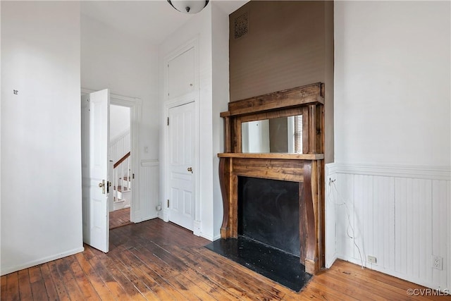 2200 E Grace St, Richmond, VA 23223 - unfurnished living room with hardwood / wood-style flooring, a fireplace with flush hearth, a wainscoted wall, and stairs