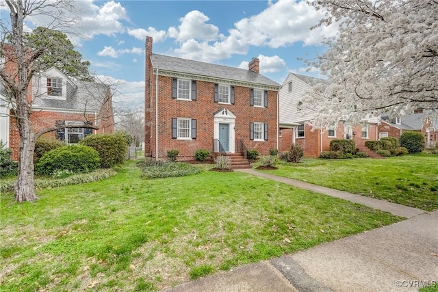 view of front of house with brick siding, a front lawn, and a chimney