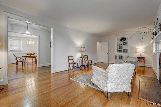 living room featuring baseboards, a notable chandelier, light wood-style flooring, and built in features