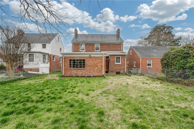 rear view of property featuring brick siding, a chimney, a fenced backyard, and a yard