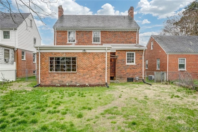 rear view of house with brick siding, a lawn, and a chimney
