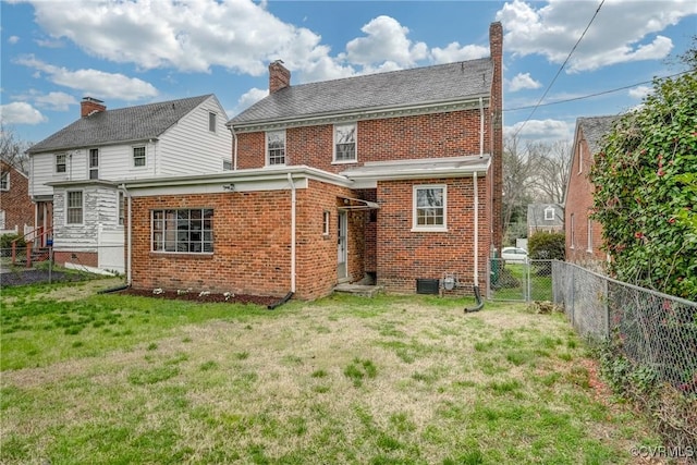 rear view of house with a fenced backyard, brick siding, and a yard