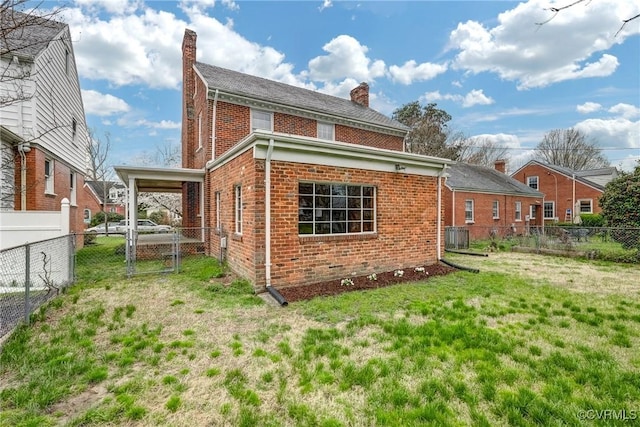rear view of property with a gate, a chimney, brick siding, a fenced backyard, and a yard