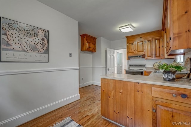 kitchen with light countertops, under cabinet range hood, light wood finished floors, white electric range, and brown cabinets