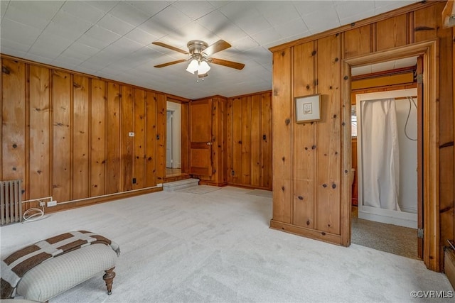 bedroom with carpet flooring, radiator heating unit, wood walls, and baseboards