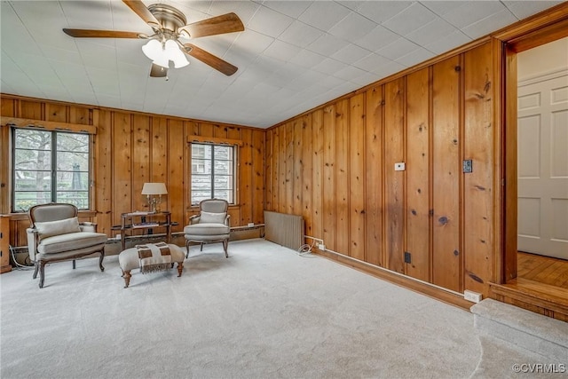 living area featuring radiator heating unit, a ceiling fan, carpet, and a wealth of natural light