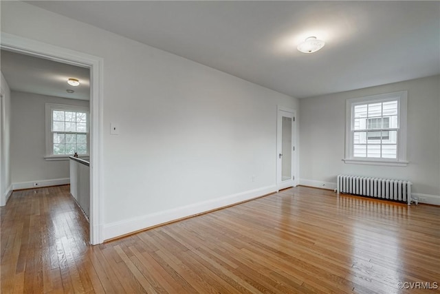 spare room featuring baseboards, radiator heating unit, and hardwood / wood-style flooring