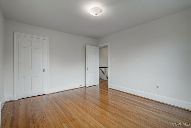 unfurnished room with baseboards and light wood-type flooring