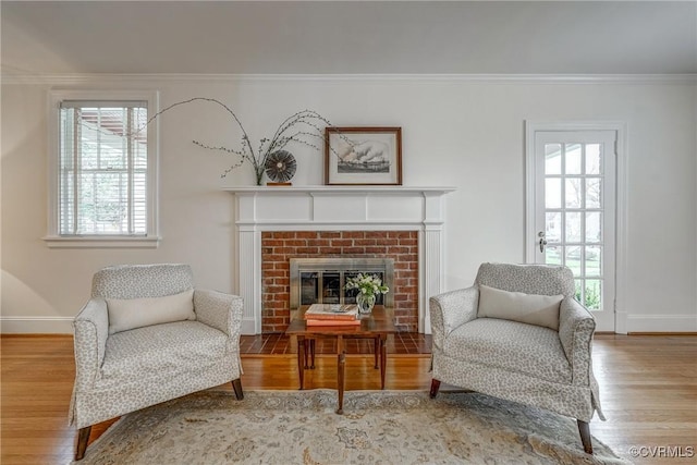 sitting room with baseboards, a fireplace, crown molding, and wood finished floors
