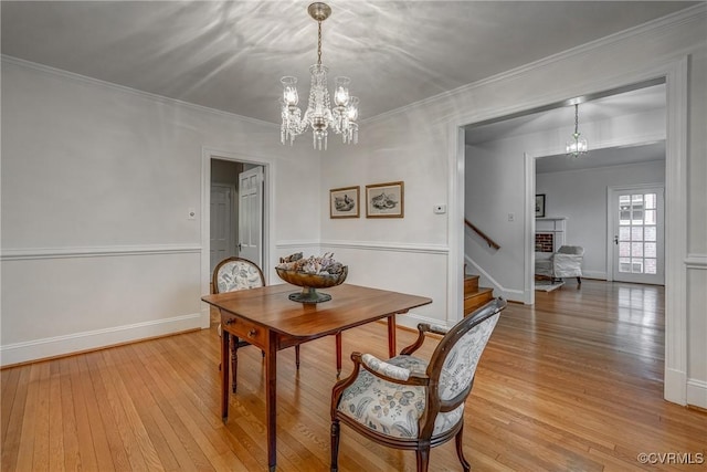 dining room with stairs, a notable chandelier, and light wood finished floors