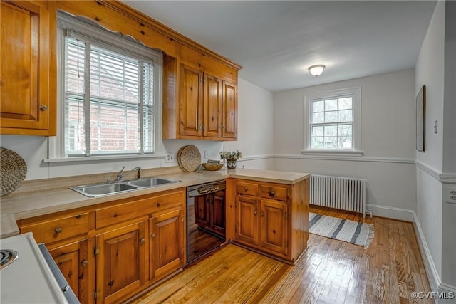 kitchen featuring light countertops, a sink, dishwasher, radiator heating unit, and brown cabinetry