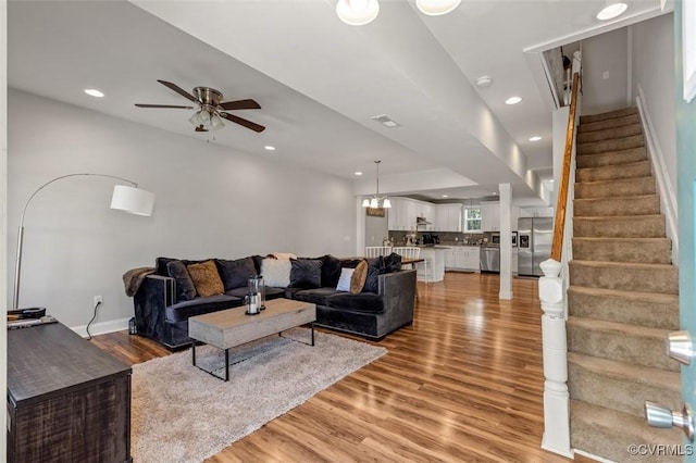 living room featuring light wood-style floors, recessed lighting, a ceiling fan, and stairs