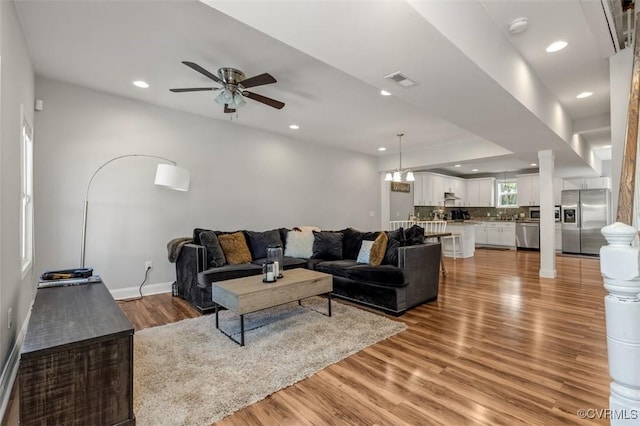 living room with visible vents, baseboards, recessed lighting, a ceiling fan, and light wood-style flooring