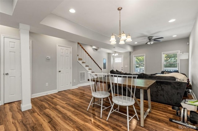 dining area with ceiling fan with notable chandelier, stairs, baseboards, wood finished floors, and visible vents