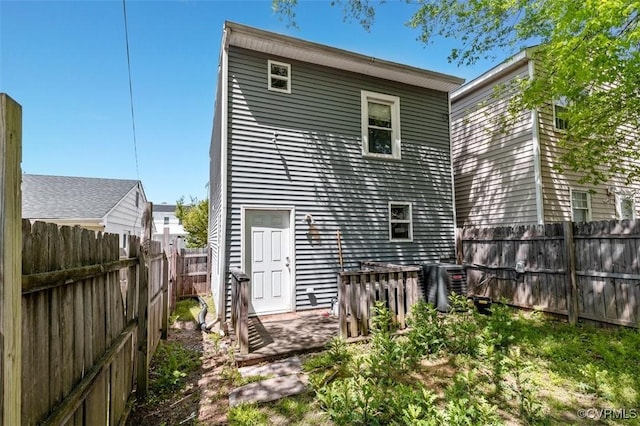 back of property featuring a fenced backyard and central AC