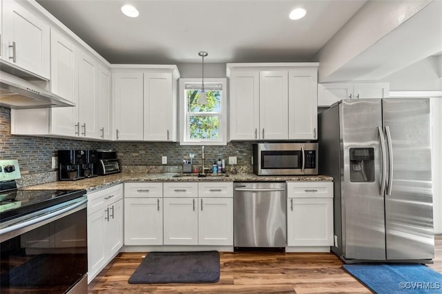 kitchen featuring decorative backsplash, light stone countertops, white cabinets, a sink, and appliances with stainless steel finishes