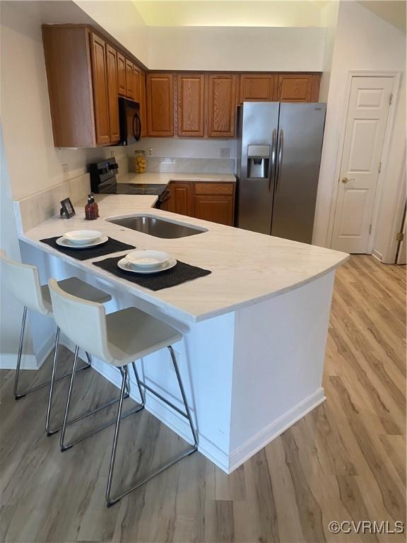 2404 Wanstead Ct, Henrico, VA 23238 - kitchen with stainless steel refrigerator with ice dispenser, light countertops, a peninsula, and brown cabinetry