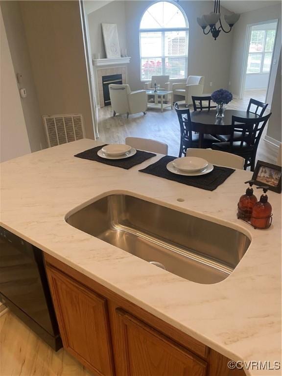 2404 Wanstead Ct, Henrico, VA 23238 - kitchen featuring brown cabinetry, light wood-style floors, a sink, and a fireplace