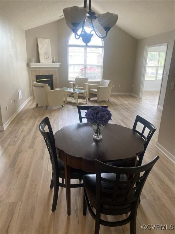 2404 Wanstead Ct, Henrico, VA 23238 - dining room featuring lofted ceiling, a tiled fireplace, light wood-type flooring, and baseboards