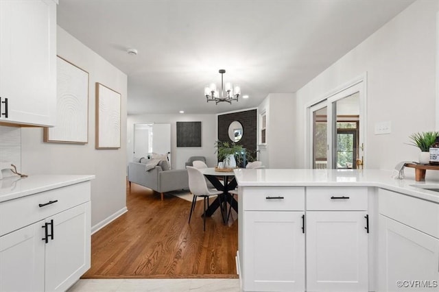 kitchen featuring light countertops, white cabinetry, a chandelier, and light wood finished floors