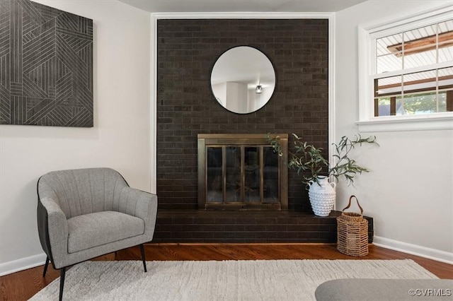 living area with wood finished floors, a fireplace, and baseboards