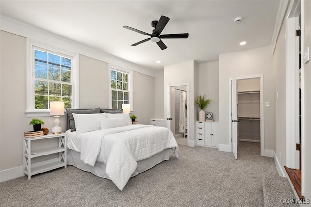 bedroom featuring light carpet, a closet, baseboards, and a spacious closet