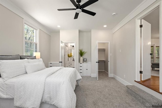 carpeted bedroom featuring ensuite bathroom, baseboards, a ceiling fan, a walk in closet, and recessed lighting