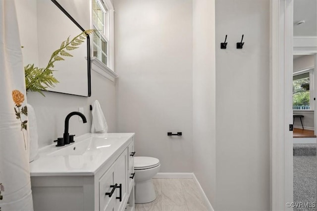 half bath with toilet, vanity, marble finish floor, and baseboards