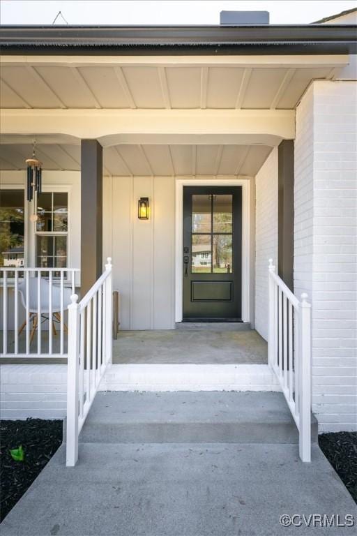 property entrance with brick siding and a porch