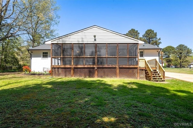 rear view of house with stairway, a sunroom, and a lawn