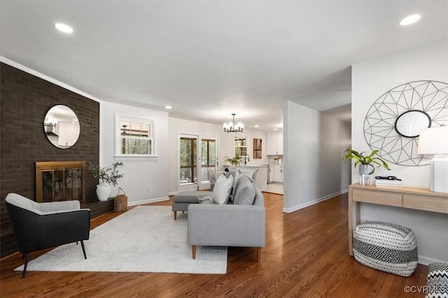 living room with an inviting chandelier, a fireplace, recessed lighting, wood finished floors, and baseboards