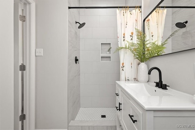 full bath featuring a tile shower and vanity