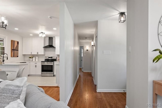 kitchen featuring wall chimney exhaust hood, light wood-style flooring, white cabinetry, light countertops, and electric stove